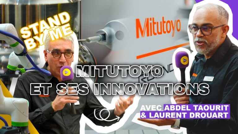 Technicien présentant une machine de métrologie automatisée Mitutoyo couplée à un robot en atelier