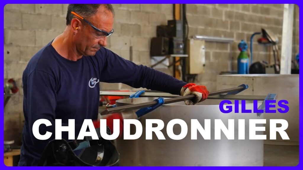 Chaudronnier dans un atelier de chaudronnerie et tuyauterie industrielle travaillant sur une pièce en tôle roulée